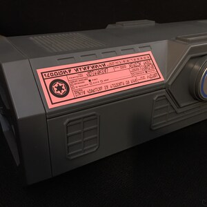 May include: A gray box with a pink label that says "1200000007 MYY7MI4M" and a Rebel Alliance symbol. The box also has a blue and silver Rebel Alliance symbol on the side.