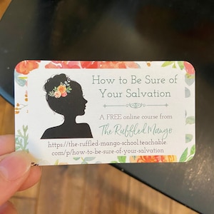 May include: A business card with a floral border and the text "How to Be Sure of Your Salvation." It features a silhouette of a woman with flowers in her hair and the website address for an online course from "The Ruffled Mango."