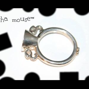 May include: A silver ring with a bell-shaped top and the text "Geisha mouse™" on the side.