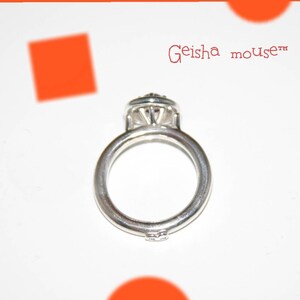May include: A silver ring with a large, clear gemstone in the centre. The ring is set on a white background with the text "Geisha mouse™" in red.