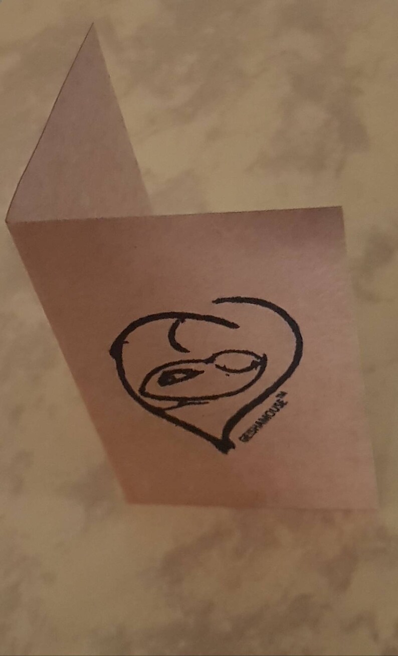 May include: A pink card with a black hand-drawn heart shape with a face inside. The text "REPHANICURE" is written below the heart.