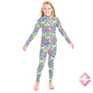 May include: A girl wearing a long-sleeved, colorful, patterned top and matching leggings. The pattern features peace signs, hearts, and other symbols.