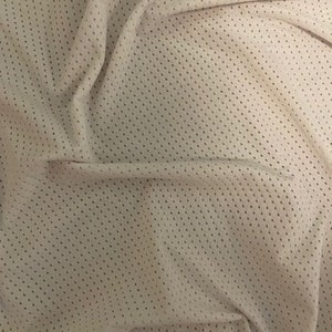 May include: Close-up of a white mesh fabric with a small, repeating diamond pattern. The fabric is soft and has a slightly textured surface.