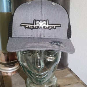 May include: A gray and black trucker hat with a silver A-10 Warthog airplane graphic. The hat has a black mesh back.