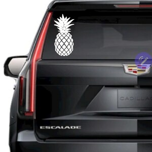 Op de afbeelding: Een witte ananas-silhouet sticker op de achterruit van een zwarte Cadillac Escalade.
