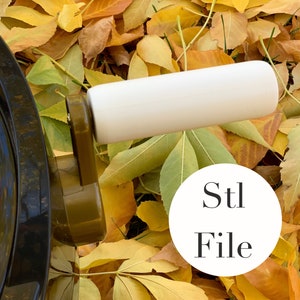 May include: A close-up of a white handle and a dark brown mechanism, possibly part of a larger device, set against a backdrop of fallen autumn leaves. A white circle with the text "Stl File" is in the image.
