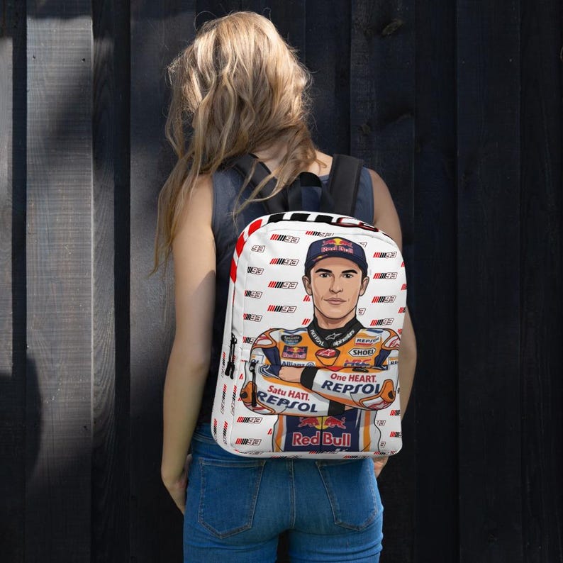 Puede incluir: Una mochila blanca con un patr&oacute;n repetitivo del n&uacute;mero 93 y un gr&aacute;fico central de un piloto de motos con un traje de carreras de la marca Repsol, una gorra oscura y el logo de Red Bull, con el texto Satu Hati, One Heart y Repsol visible.