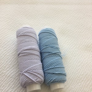 May include: Two spools of thread, one light purple and one light blue.