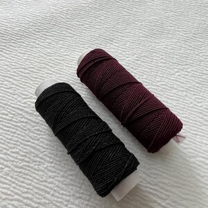 May include: Two spools of thread, one black and one burgundy.