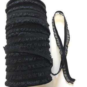 May include: A roll of black elastic trim with a ruffled edge. The trim is wound around a cardboard spool.