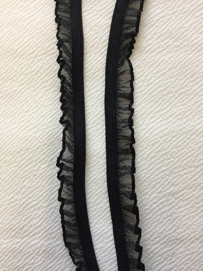May include: Two black elastic trims with a ruffled edge. The trim is made of a sheer fabric with a subtle shimmer.