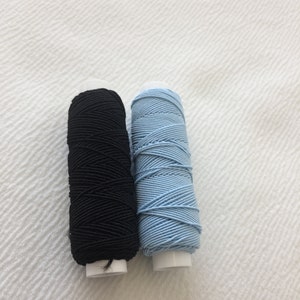 May include: Two spools of thread, one black and one light blue.