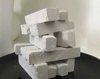 Può includere: Un mucchio di bastoncini di gesso bianco su una superficie nera. I bastoncini di gesso sono disposti a scalare.