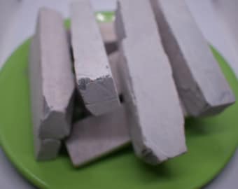 Può includere: Un mucchio di bastoncini di gesso bianco su un piatto verde. I bastoncini di gesso sono disposti in modo casuale.
