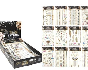 May include: A display box of 12 sheets of gold and silver metallic temporary tattoos. The tattoos feature various designs including feathers, geometric shapes, and jewelry. The box is labeled "Glam & Glamour Metallic Tattoos".