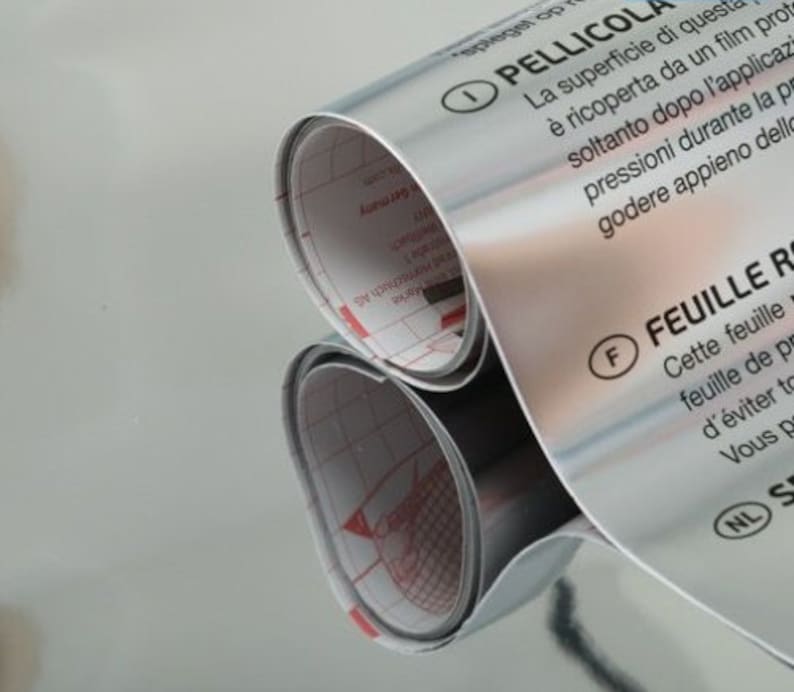 Może przedstawiać: Rulon srebrnej folii samoprzylepnej z instrukcjami w języku włoskim i francuskim. Tekst głosi "Pellicola" i "Feuille Re", co wskazuje, że folia jest przeznaczona do naklejania na powierzchnię.