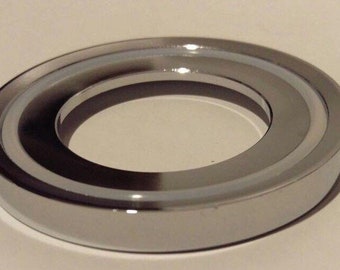 May include: A chrome-plated metal ring with a white inner ring. The ring has a smooth, polished finish.