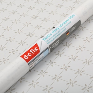 Könnte beinhalten: Eine Rolle d-c-fix statische Haftfensterfolie für Privatsphäre und Dekoration. Das Etikett enthält den Text "Static cling window film" in mehreren Sprachen. Die Rolle ist weiß mit einem floralen Muster.