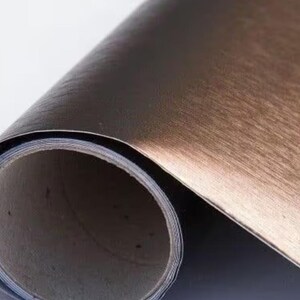 May include: A roll of brushed copper-coloured self-adhesive vinyl film. The film has a metallic finish and is designed for decorative and craft projects.
