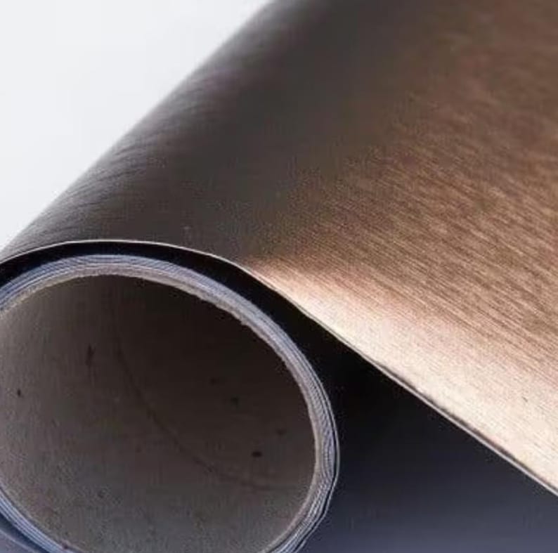 May include: A roll of brushed copper-coloured self-adhesive vinyl film. The film has a metallic finish and is designed for decorative and craft projects.