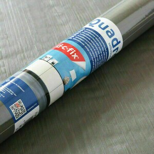 May include: Roll of gray self-adhesive contact paper with the text "quadrat selbstklebend" and "dc-fix" printed on the label. The label also includes a QR code and the text "Made in Germany".