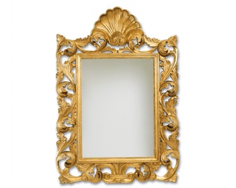 Puede incluir: Un espejo dorado adornado con una parte superior en forma de concha y tallas intrincadas. El espejo es rectangular y tiene un borde biselado.