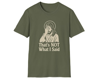 May include: Olive green t-shirt featuring a graphic of Jesus with his hand over his face, and the text "That's NOT What I Said" in a bold, white font. The shirt has a crew neck and short sleeves.