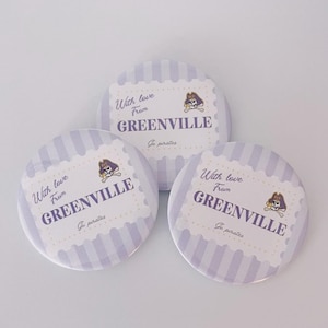 Könnte beinhalten: Drei runde Buttons mit einem hellvioletten und weißen Streifenmuster. Jeder Button zeigt den Text "With love From GREENVILLE" in Dunkelviolett, zusammen mit einem Totenkopf- und gekreuzten Knochen-Logo. Die Worte "Go pirates" sind ebenfalls zu sehen.
