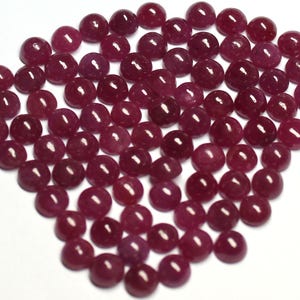 Peut inclure: Un ensemble de pierres précieuses cabochon de couleur rouge foncé. Les pierres polies, de forme ronde, présentent une finition lisse et brillante. Les pierres sont disposées sur une surface blanche, créant une présentation visuellement attrayante. Ces pierres conviennent à la création de bijoux.
