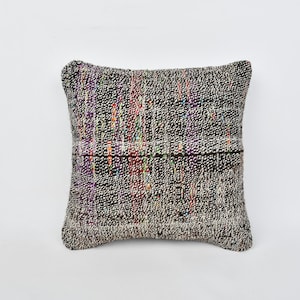May include: A square throw pillow with a black and white woven pattern. The pillow has a subtle iridescent sheen and a slightly textured surface.