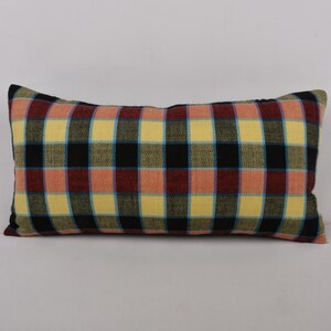 May include: A rectangular pillow with a plaid pattern in shades of yellow, red, black, and blue.