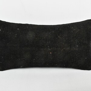 May include: A rectangular black pillow with a textured surface. The pillow is a solid black color and appears to be made of a woven fabric. The pillow is placed on a white background.