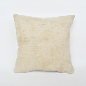 May include: A plain off-white square pillow with a subtle texture. The pillow is made of a soft, natural fabric.
