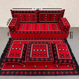 Peut inclure: Un ensemble de canapé rouge et noir avec coussins et tapis assortis. Le canapé mesure 190 cm de large et présente un motif géométrique. L'ensemble comprend deux coussins carrés, deux coussins rectangulaires et un tapis à bordure frangée.