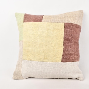 Puede incluir: Cojín decorativo cuadrado con diseño de patchwork. El cojín presenta una combinación de colores verde claro, amarillo, burdeos y beige. El cojín está hecho de tela tejida y tiene forma cuadrada.