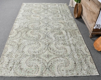 May include: A vintage rug with a light beige background and a brown floral pattern. The rug has a distressed look and is perfect for adding a touch of bohemian style to any room.