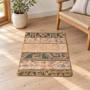 Può includere: Un tappeto rettangolare con un design patchwork composto da fasce orizzontali con motivi vari in tonalità tenui di blu, beige, rosa e verde. Il tappeto presenta una consistenza a pelo corto e un bordo rifinito, mostrando un mix di motivi geometrici e floreali.