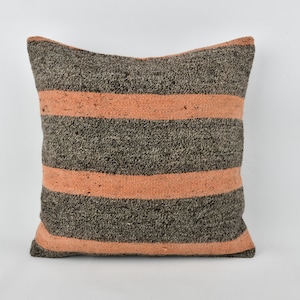 May include: A striped throw pillow with a gray and peach color scheme. The pillow is made of a soft, textured fabric.