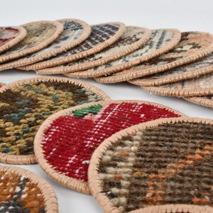 May include: A set of colorful round coasters made from woven fabric with a beige trim. The coasters feature various patterns and colors, including red, green, brown, and beige.