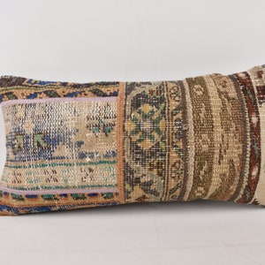 May include: A rectangular pillow with a patchwork design. The pillow is made of different fabrics with various patterns and colors, including brown, blue, green, and beige.