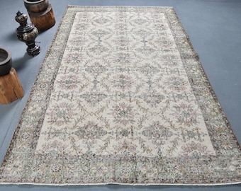 May include: A vintage cream-colored rug with a floral pattern in shades of green, pink, and brown. The rug has a border with a more intricate design.