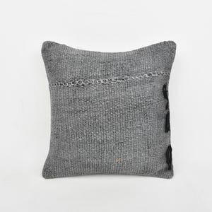 May include: Gray square throw pillow with black embroidered details. The pillow is made of a textured fabric.