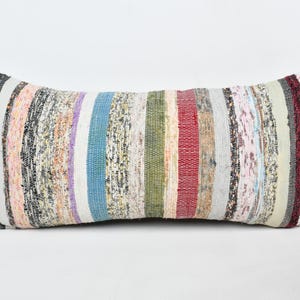 Op de afbeelding: Rechthoekig decoratief kussen met een streepjespatroon. Het kussen heeft verticale strepen in verschillende kleuren, waaronder zwart, wit, roze, paars, blauw, groen en rood. Het is gemaakt van een geweven stof.