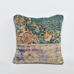 May include: A square teal and blue throw pillow with a floral pattern. The pillow is made from a patchwork of different fabrics.