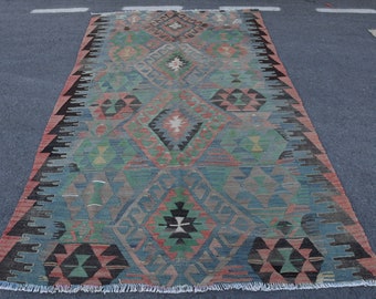 May include: A vintage rug with a geometric pattern in shades of blue, green, red, and black. The rug has a fringed edge and is woven with intricate details.
