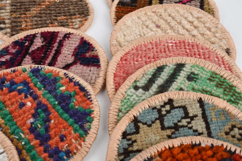 May include: A stack of colorful round woven coasters with a leather trim. The coasters feature various patterns and colors, including red, blue, green, and orange.
