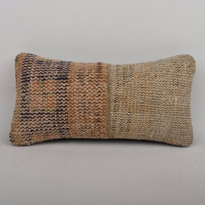 May include: A rectangular pillow with a woven fabric cover. The pillow is made of a patchwork of different colored fabrics, including beige, brown, and blue. The pillow is perfect for adding a touch of bohemian style to any room.