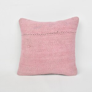 May include: A pink woven throw pillow with a subtle textured pattern and a decorative stitch detail around the edges.