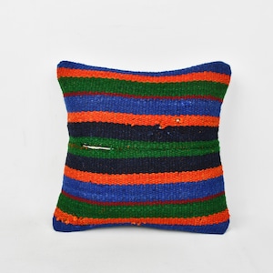 May include: A square-shaped throw pillow with a striped pattern in shades of blue, green, and orange. The pillow is made of woven fabric and has a slightly distressed look.