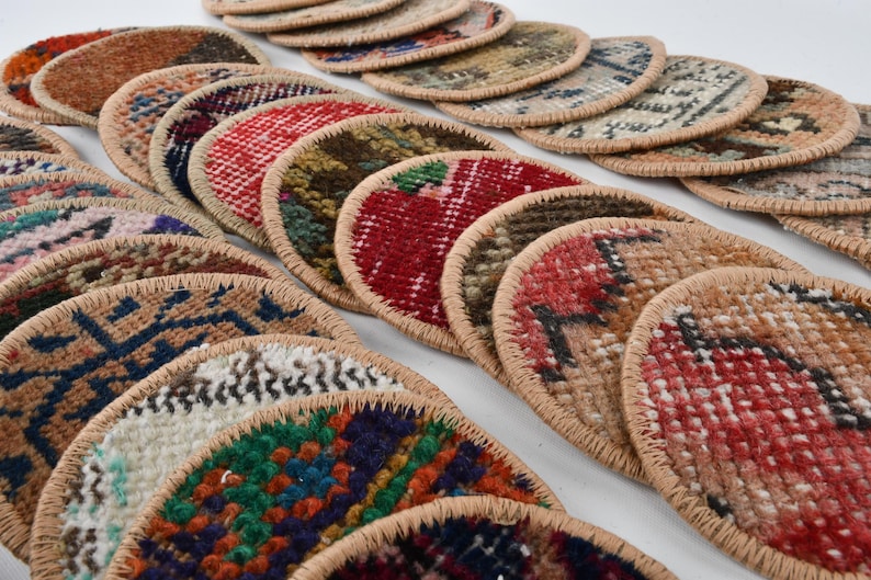 May include: A collection of colorful round woven coasters with a beige trim. The coasters feature various patterns and designs.
